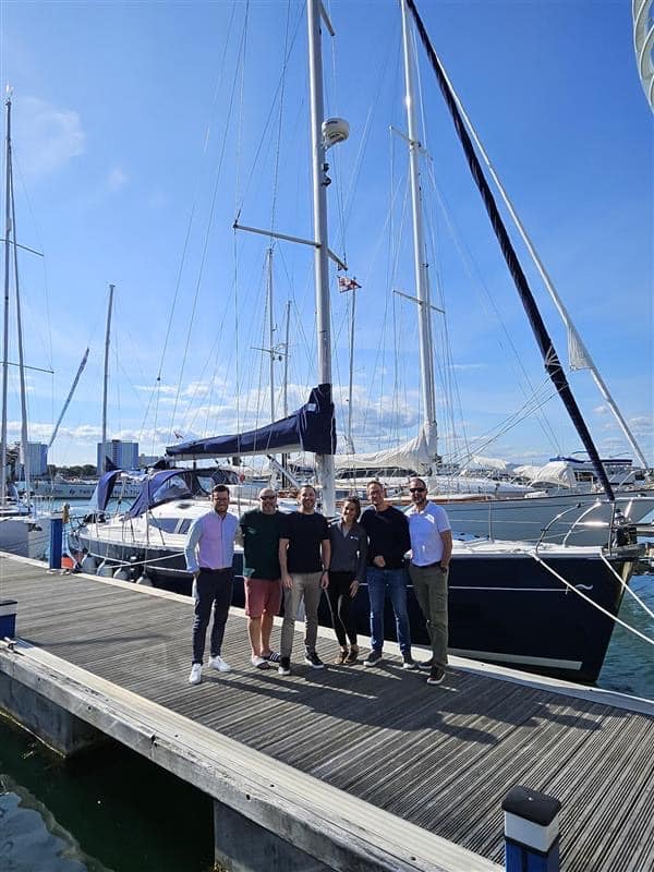 6 Energi Team members stood next to a yacht on a sunny day